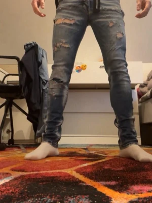 Blå slitna skinny jeans med hål - Säljer ett par blå skinny jeans med slitningar och hål på både lår och knän. Jeansen har en klassisk femficksmodell och är tillverkade i denim med stretch för skön passform. Perfekta för en avslappnad och trendig look.