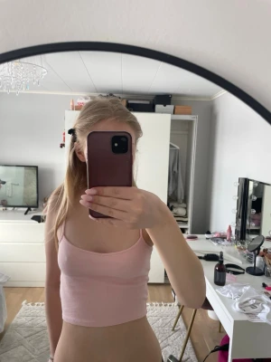 Ljusrosa ribbad croppad linnetopp Monki - Säljer en ljusrosa croppad linnetopp från Monki. Toppen är ribbad och har smala axelband, perfekt för att skapa en chill och snygg look. Materialet är mjukt och stretchigt, vilket gör den bekväm att bära under varma dagar.