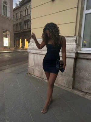 Marinblå kort klänning med smala axelband - Snygg marinblå kort klänning med smala axelband och figurnära passform. Perfekt för dig som gillar en stilren och enkel look. Klänningen har en minimalistisk design och passar dig som vill sticka ut på stan.