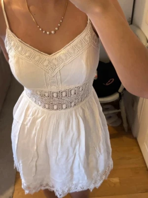 Vit sommarklänning med spetsdetaljer - Söt vit kortklänning med tunna axelband och v-ringad hals från Abercrombie & Fitch. Perfekt skick och fina detaljer 