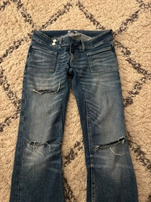 GinaTricot Pleated flare jeans  - Säljer ett par pleated flare jeans från GinaTricot med slitningar på knäna. De är i samma färg som på andra bilden bara att ljuset gör att de ser mörkare ut än vad de är. Jeansen är lågmidjade, de ärsjälv nedsydda för att bli tajtare i benen och lite längre. Orginalpris 399kr. Väldigt fint skick.