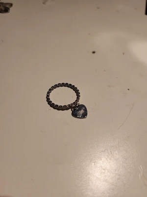 Tre silverfärgade ringar med hjärtdetaljer - Säljer tre stilrena ringar i silverfärg. Den ena har en tvinnad design med ett hängande hjärta, medan den andra är slät med ett fast hjärta framtill. Perfekta accessoarer för dig som gillar enkla men söta smycken.