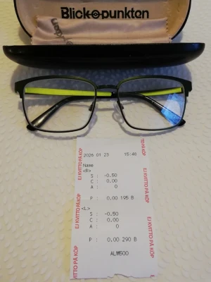 Svarta glasögon från Blickpunkten - Unisex glasögon med metallbåge i svart och grön färg. Glasögonen har justerbara näskuddar och rektangulär form. Passar för olika användningsområden där synkorrigering krävs. Läsglasögon med låg dioptri – mycket gott skick. Ingen cylinder/astigmatism. Glasen är klara utan synliga repor och bågen är rak och stabil. Ej använda. Styrka på glasögonen: Höger (R): S -0,50/Vänster (L): S -0,50. Ingår: glasögon, originalfodral och rengöringsduk.  Dioptrikvitto med styrkeuppgifter kan visas vid affär.