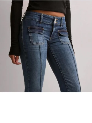 Blå jeans med fickdetaljer - Snygga blå jeans med utsvängda ben och fickor framtill. Jeansen har hög midja, bälteshällor och klassisk femficksdesign. Materialet är denim i en tvättad blå nyans som ger en cool och avslappnad look.