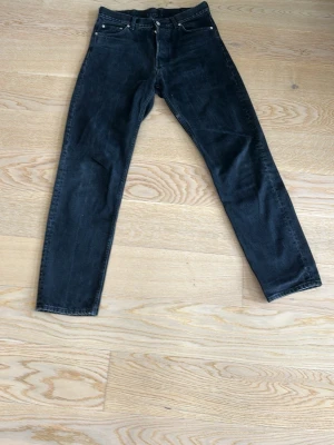 Svarta raka jeans - Säljer ett par svarta jeans med rak passform och klassisk femficksdesign. Jeansen har normal midja och stängs med knapp och dragkedja. Perfekta till en avslappnad stil och funkar året runt.
