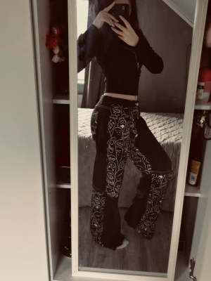 Svarta jeans med vita ansikten - Unika svarta jeans med vita grafiska ansikten och figurer tryckta över hela byxorna. Modellen är utsvängd med mellan-låg midja och cool streetwear-vibe. Perfekta för dig som vill sticka ut och gillar konstnärliga detaljer.
