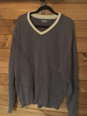 Grå ribbstickad tröja från Friday - stilren & bekväm - Snygg grå ribbstickad tröja från Friday med V-ringning och vit kontrastkant vid halsen. Mjuk och skön i materialet och passar perfekt till både vardag och mer uppklädda outfits. Lätt att matcha med jeans eller chinos. • Märke: Friday • Färg: Grå med vit detalj • Skick: Bra skick • Stil: Ribbstickad, V-ringad • Material: 100% bomull • Storlek: L Säljes eftersom den inte används längre. *t