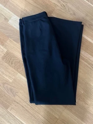 Svarta raka kostymbyxor - Snygga svarta kostymbyxor med rak passform och klassisk midja. Byxorna har diskreta pressveck och enkel design utan synliga detaljer. Perfekta för en stilren look och passar till många olika outfits.