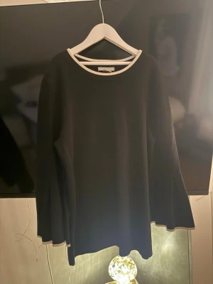 Svart  tröja med vida ärmar - Snygg svart  tröja med kontrasterande vit kant vid halsringning och ärmslut. I storlek S från hm