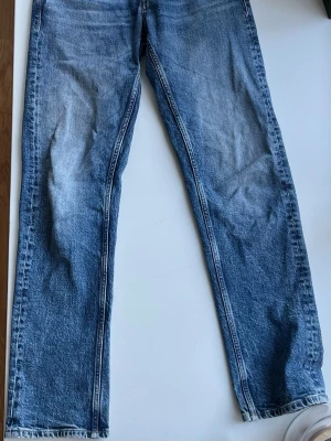 Blå straight fit jeans från Replay - Säljer ett par blå jeans från Replay, modell Grover med straight fit. Jeansen har klassisk femficksdesign, slitningar och kontrastsömmar. Tillverkade i denim med snygg tvättad look och kopparfärgade detaljer. Perfekta för en avslappnad och trendig stil.