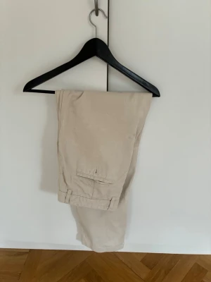 Beige chinos från A Day's March - Snygga beige chinos från A Day's March i en mjuk mix av 65% tencel och 35% bomull. Klassisk passform med fickor bak och stilren look. Perfekta för dig som gillar en clean och enkel stil.