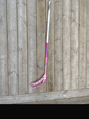 Fat pipe innebandyklubba rosa - Säljer en innebandyklubba från fat pipe i rosa med blå detaljer och vitt grepp. Klubban har ett plastblad och ett långt skaft med tydlig fatpipe-logga. Perfekt för dig som vill sticka ut på planen!