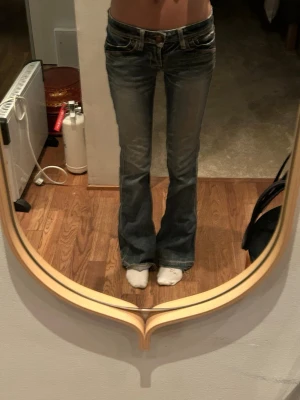 Bootcut jeans med låg midja - Säljer ett par klassiska blå bootcut jeans med låg midja och slitningar framtill.  Passar S/XS