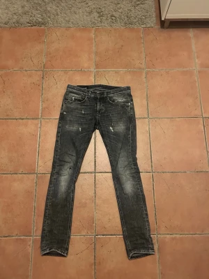 Dondup jeans - Säljer ett par grå/svarta dondup jeans med lite slitningar och gråa nyanser. Jeansen har fem fickor. Jeansen är perfekt för en ren stil. De är inprincip helt oanvända. Hör av er vid fler frågor!