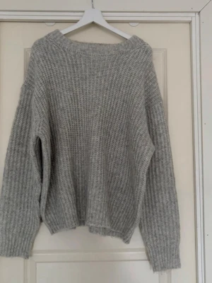 Grå oversized stickad tröja. XL - Mysig grå stickad tröja med oversized passform och bred ribbstickning. Tröjan har rund halsringning och långa ärmar med ribbade muddar. Perfekt för lager på lager och en avslappnad stil.