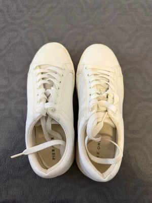 Vita låga sneakers från Pier One - Stilrena vita sneakers från Pier One med klassisk låg profil. Skorna har vita snören, diskreta sömmar och ovandel i slätt syntetmaterial. Perfekta för dig som gillar en clean och enkel look till vardagsoutfiten. Perfekta skor för studenten, endast använda en gång 
