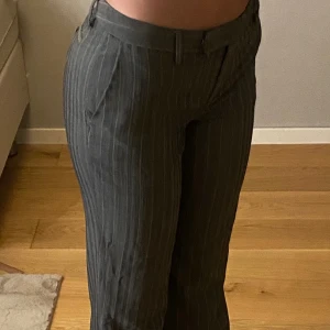 Massimo Dutti kostymbyxor - Snygga grå kostymbyxor med vita kritstrecksränder och smal passform. Byxorna har hällor för skärp, snedställda fickor fram och pressveck längs benen. Perfekta för en stilren och trendig look.