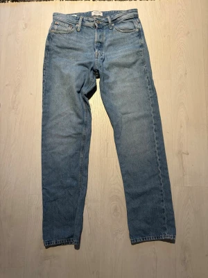 Ljusblå raka jeans från Jack & Jones - Säljer ett par ljusblå jeans från Jack & Jones med klassisk rak passform. Jeansen har en snygg vintagekänsla och är tillverkade i bomull. Perfekta för en avslappnad och trendig stil. W30 L32