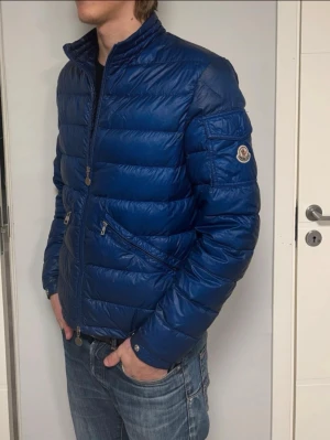 Moncler Agay - En lite schysstare Moncler jacka i modellen Agay. Den är perfekt nu till våren, inte för tunn, inte för tjock! Jackan är rätt sliten som ni ser men det är ingenting man tänker på när man har på sig den! (Strlk 3 i Moncler, passar M)