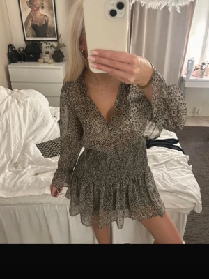 Leopardmönstrad kort klänning - Säljer en snygg kort klänning med leopardmönster. Klänningen har v-ringning, långa ärmar med volang vid ärmslut och en volangkantad kjol. Tillverkad i ett tunt, luftigt material. Från Zara i storlek xs.