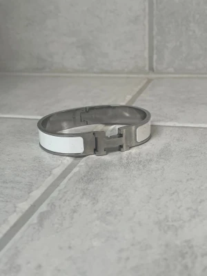 H armband - Snyggt armband i färgerna silver och vit. Armbandet är i mycket bra skick. Ingen låda eller tillbehör finns kvar tyvärr