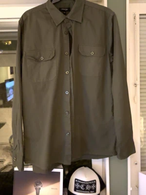 Olivgrön skjorta/overshirt  - Stilren olivgrön skjorta från on our terms med klassisk krage och två bröstfickor med knappar. Skjortan/overshirten är i ett väldigt bra skicka och nästan aldrig användning. Hör av dig vid minsta fundering 