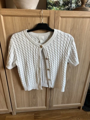 Vit stickad kofta - Kortärmad stickad kofta från H&M i storlek S med guld knappar. Jätte fin och passar  till allt!!😽