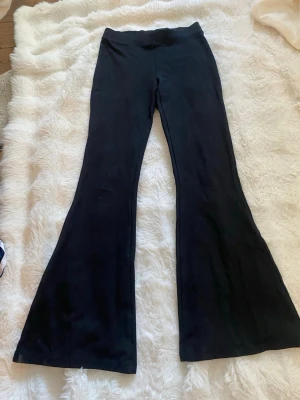 Svarta utsvängda leggings Gina Tricot - Säljer ett par svarta leggings från Gina Tricot i storlek XS. De har utsvängda ben och är tillverkade i ett mjukt stretchigt material med viskos, polyester och elastan. Perfekta för en trendig och bekväm look.