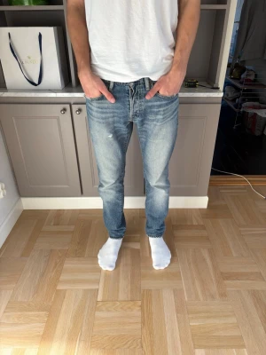 Ralph Lauren jeans - Säljer ett par blå Ralph Lauren Denim and Supply jeans med snygga slitningar och tvättad look. Jeansen har klassisk femficksmodell, normal midja och raka ben. Perfekta för en avslappnad och trendig stil. Sitter som ett par 30/30. Jag ör 178 cm och väger 65 kg.