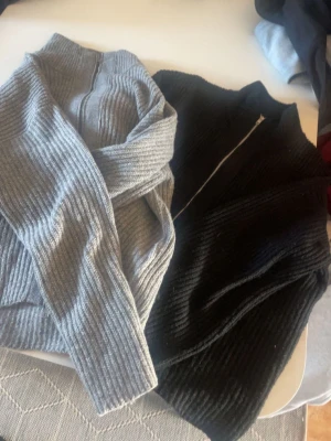 Två ribbstickade ziptröjor - Säljer två ribbstickade tröjor med dragkedja, en i svart och en i grått. Båda har hög krage och är tillverkade i ett tjockare, mjukt material som passar perfekt när det är kallt. Tröjorna har en avslappnad passform och långa ärmar. Båda ifrån LAGER 157 och säljer det som ett sätt tsm. Två för 200 och en för 150