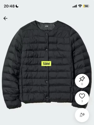Blå dunjacka från Uniqlo - Minimalistisk blå dunjacka från Uniqlo med rund halsringning och tryckknappar framtill. Jackan har en quiltad design och är lätt vadderad, perfekt för kalla vinterdagar. Enkel och stilren modell utan huva eller synliga fickor.