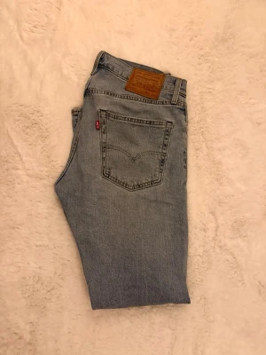 Levi's 512 Premium ljusblå raka jeans - Säljer ett par klassiska ljusblå Levi's Premium jeans med rak passform. Jeansen har fem fickor, Levi's ikoniska röda tag på bakfickan och patch i läder bak i midjan. Tillverkade i slitstark bomullsdenim, perfekta för en avslappnad look.
