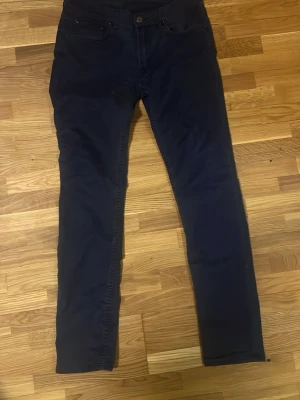 Mörkblå slim fit jeans från acne studios  - Snygga mörkblå slim fit jeans med klassisk femficksdesign och knappgylf. Jeansen har smal passform och raka ben, perfekta för en stilren och modern look. Materialet känns mjukt och stretchigt för extra komfort.
