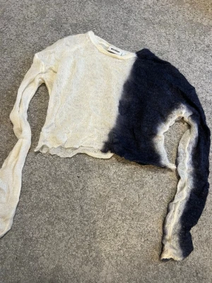 Tröja från Weekday - Säljer en tunnstickad tröja från Weekday i vit och svart dip dye. Tröjan har lång ärm, rund halsringning och råa kanter. Materialet är lätt och transparent, perfekt för lager på lager. 