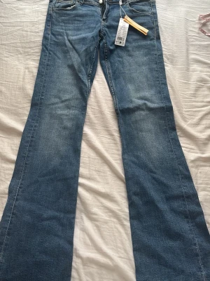 Blåa flare jeans med fickor - Säljer ett par snygga blåa flare jeans från Ginatricot i modellen 'Flare pocket jeans tall'. Jeansen har klassiska fickor fram och bak, hög midja och utsvängda ben. Perfekta för dig som gillar retrovibbar och vill ha en trendig look. De är aldrig använda, nypris är 350, därför säljer jag för 300kr. 