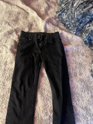 Svarta Armani skinny jeans med nitar - Svarta skinny jeans med nitar på bakfickorna och dubbla knappar fram. Klassisk femficksmodell med smal passform och låg midja. Perfekta till en trendig streetstil. Pris kan diskuteras vid snabb affär