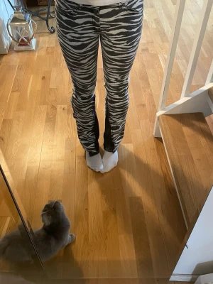 as coola jeans  - Säljer ett par zebramönstrade jeans i svart och vitt med utsvängda ben. Jeansen har låg midja och dragkedja med knapp framtill. Perfekta för dig som vill sticka ut med ett djurmönster!