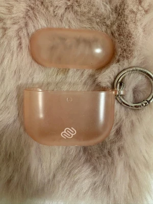 Rosa genomskinligt AirPods-fodral - Säljer ett rosa genomskinligt AirPods-fodral från Ideal of Sweden. Fodralet har en mjuk, matt finish och är utrustat med en silverfärgad nyckelring så du enkelt kan fästa det på väskan eller nyckelknippan. Perfekt för dig som vill skydda dina hörlurar med stil.