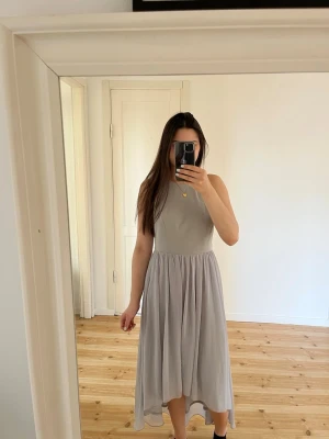 Ljusgrå långklänning från Goddiva - Elegant ljusgrå långklänning från Goddiva med ärmlös design och rund halsringning. Klänningen har ett flytande, lätt tyg. Perfekt för dig som vill ha en stilren och modern look.☺️Nypris 800kr