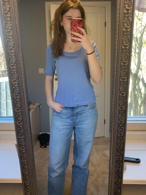 Ljusblå basic t-shirt - Ljusblå t-shirt med normal passform och 1/3 ärmar. T-shirten har rund halsringning och är tillverkad i bomull. Jag är 174 cm lång.