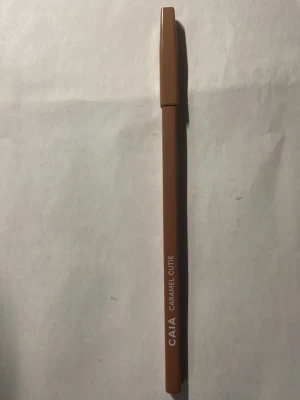 CAIA Caramel Cutie läppenna - Snygg läppenna från CAIA i färgen Caramel Cutie. Pennan har en varm karamellbrun ton och kommer i klassisk pennform med lock. Perfekt för att definiera och framhäva läpparna med en naturlig look.