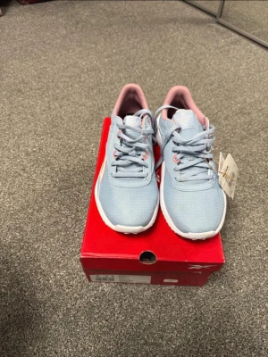 Ljusblå Reebok sneakers med rosa detaljer - Snygga ljusblå sneakers från Reebok med rosa detaljer och vita sulor. Skorna har mesh-överdel för bra andningsförmåga, klassisk Reebok-logga på sidan och matchande ljusblå skosnören. Perfekta för en sportig och trendig look.