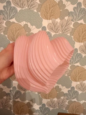 2st Rosa lampskärmar - Säljer två unika rosa lampskärmar med vriden, vågig form och räfflad yta. Tillverkad i plast och passar perfekt för dig som vill ha en cool och modern detalj i rummet. Skärmen ger ett mjukt och behagligt ljus när den är tänd. Höjden på skärmen är 16cm och 16cm vid sin bredaste punkt. Säljer endast lampskärmarna. Passar till e14 sockel.