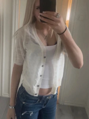 Vit croppad linnetopp med knappar - Säljer en vit croppad linnetopp med korta ärmar och knappar framtill. Toppen är tunn och lätt, perfekt för varmare dagar. 