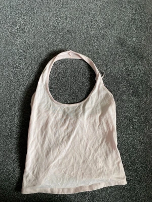 Ljusrosa ärmlös linnetopp - Säljer en ljusrosa ärmlös linnetopp med halterneck och enkel design. Toppen är gjord i mjuk bomull och har en smickrande passform som passar perfekt till sommaren. Perfekt att styla med jeans eller kjol för en trendig look💕🥂