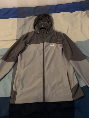 Grå vindjacka från Under Armour - Snygg tvåfärgad grå vindjacka från Under Armour, ganska ny inte använt så mycket.