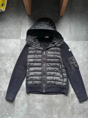 Moncler jacka - Säljer en snygg moncler cardigan i toppskick.  Enda lilla anmärkninger är vid ena ärmen som visas på bild. Inget man tänker på vid användning.  Svart storlek M.  Äkthetsbevis finns på de sista bilden. Bedöm skick själv utifrån bilderna.