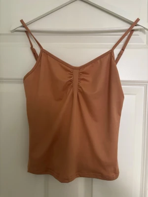 Beige croppad linnetopp med rynk - Säljer en beige croppad linnetopp med smala axelband och snygg rynkdetalj framtill i storlek M.