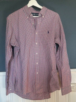 Ralph lauren skjorta - Ralph lauren skjorta i storlek L i vitt,rött blått rutigt tema med mörk blå logga. Riktigt fint skick utan någon sorts deffekter.