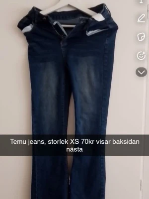 Mörkblå utsvängda jeans från Temu - Säljer ett par mörkblå jeans från Temu i storlek XS. Jeansen har utsvängda ben och snygga detaljer på bakfickorna med röd och vit brodyr. Klassisk femficksmodell och tillverkade i denim med lätt tvättad look. Perfekta för en trendig och avslappnad stil.